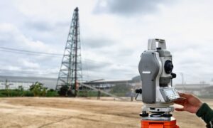 Land surveyor using a total station near utility infrastructure during an ALTA survey utilities assessment